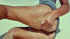 Blonde relaxes by the sea, showing off her curves in the sand