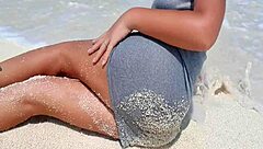 Blonde relaxes by the sea, showing off her curves in the sand