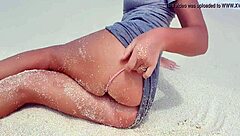 Blonde relaxes by the sea, showing off her curves in the sand