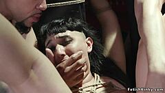 Pawg individual experiences double interaction while restrained. This occurs in a group setting with varied participants.